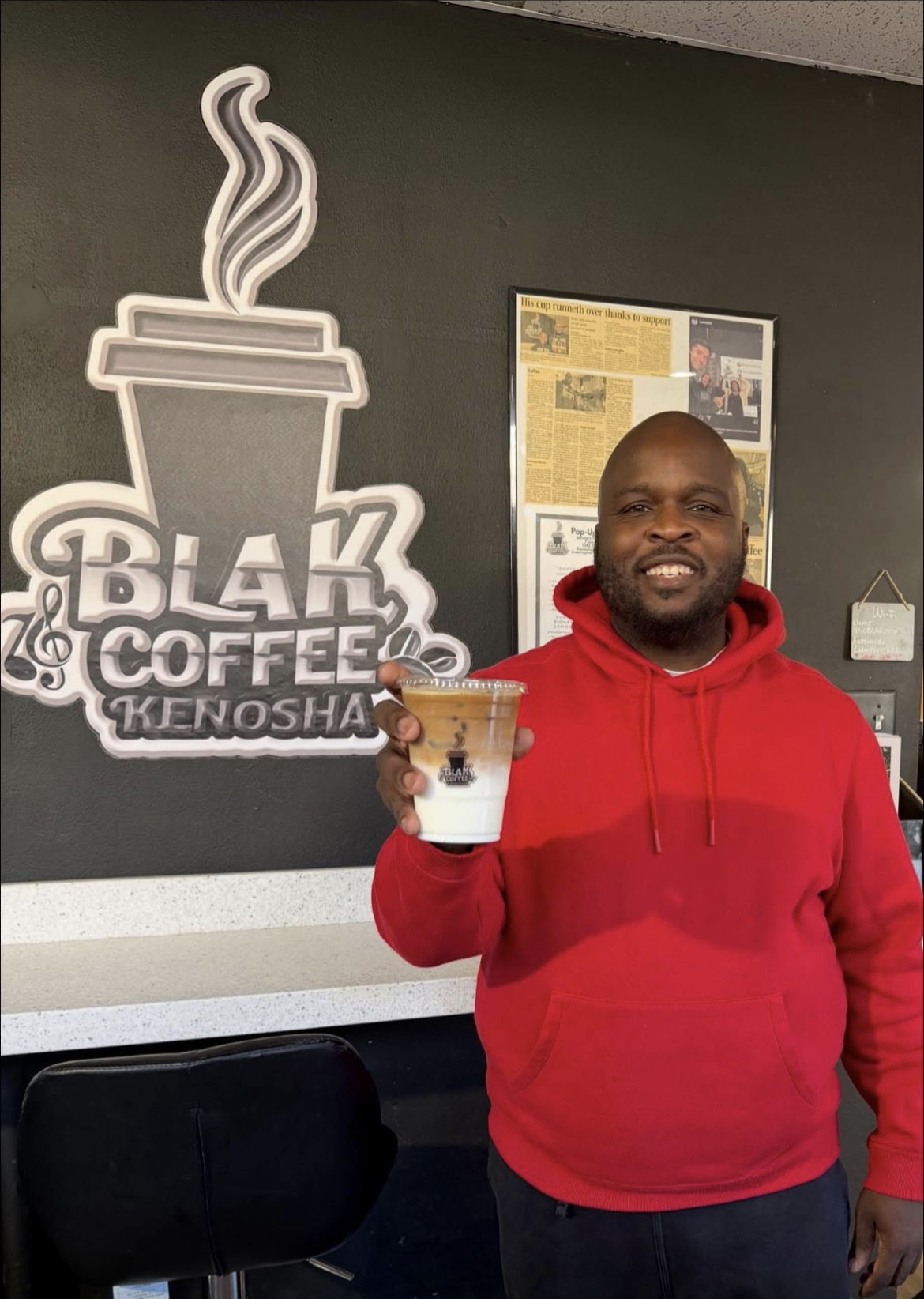 BLAK Coffee owner DeShaun Foster holding a signature iced drink